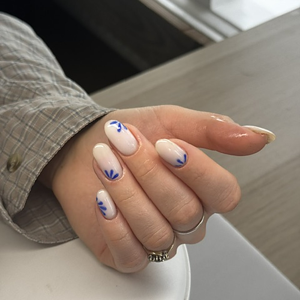 Nude nagels met handgeschilderde kobaltblauwe blaadjes