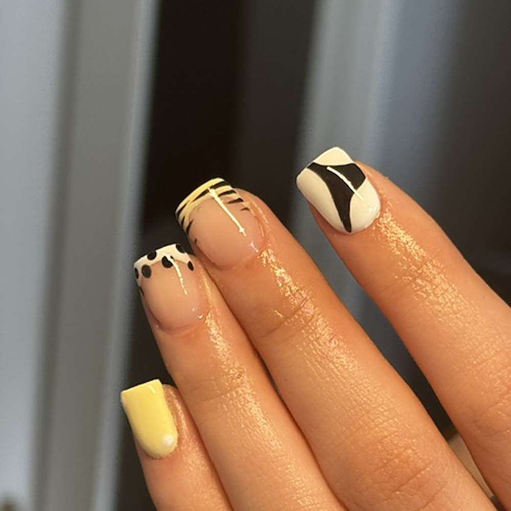 Vierkant gevijlde nagels in zachtgeel met zwart-witte nagelart en gouden lijnen